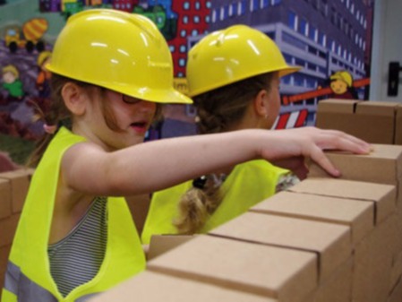 Zwei Kinder bauen ein begehbares Haus aus Kartonbausteinen